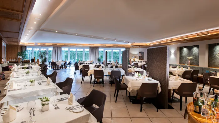 Elegantes Hotelrestaurant mit gedeckten Tischen, moderner Einrichtung und Tageslicht